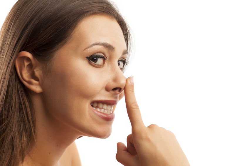 Beautiful smiling young woman touching her nose on white background