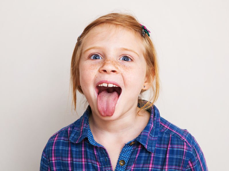 Happy redhead little girl showing her tongue.